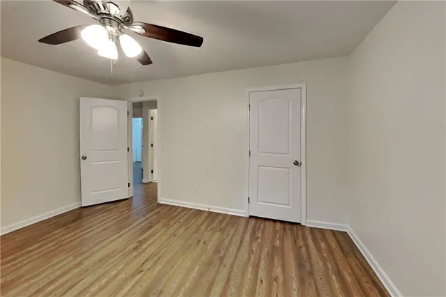 an empty room with wooden floor chandelier fan and windows