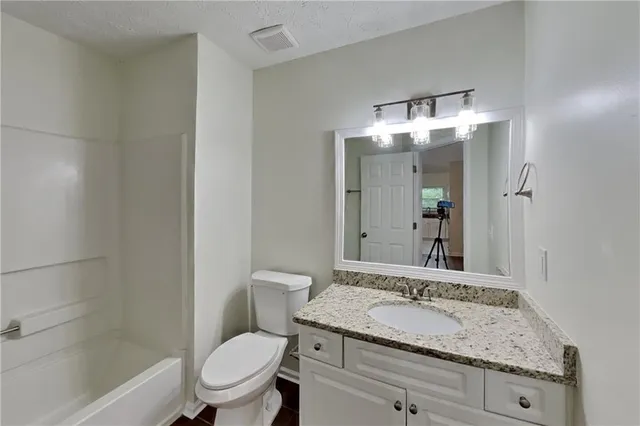 a bathroom with a granite countertop sink toilet and shower