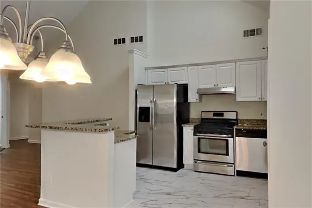 a kitchen with stainless steel appliances granite countertop a stove a refrigerator and a sink