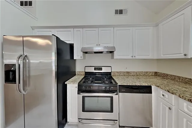 a kitchen with stainless steel appliances granite countertop a stove and a refrigerator