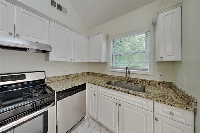 a kitchen with granite countertop white cabinets and a stove top oven