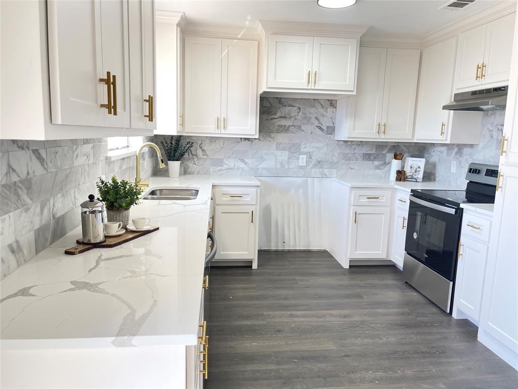 a kitchen with stainless steel appliances white cabinets a sink and a stove