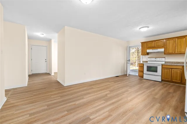 a view of a kitchen with a stove wooden cabinets and entryway