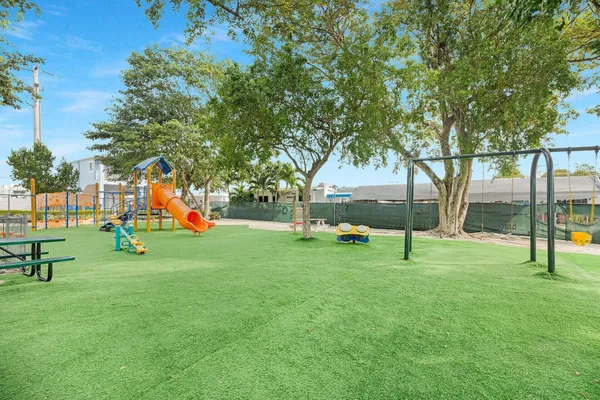 a view of a tennis ground with huge green field and trees in the background