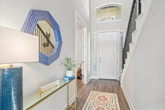 a view of front door with hallway and wooden floor