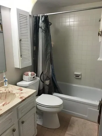 a bathroom with a granite countertop bathtub shower sink vanity and toilet