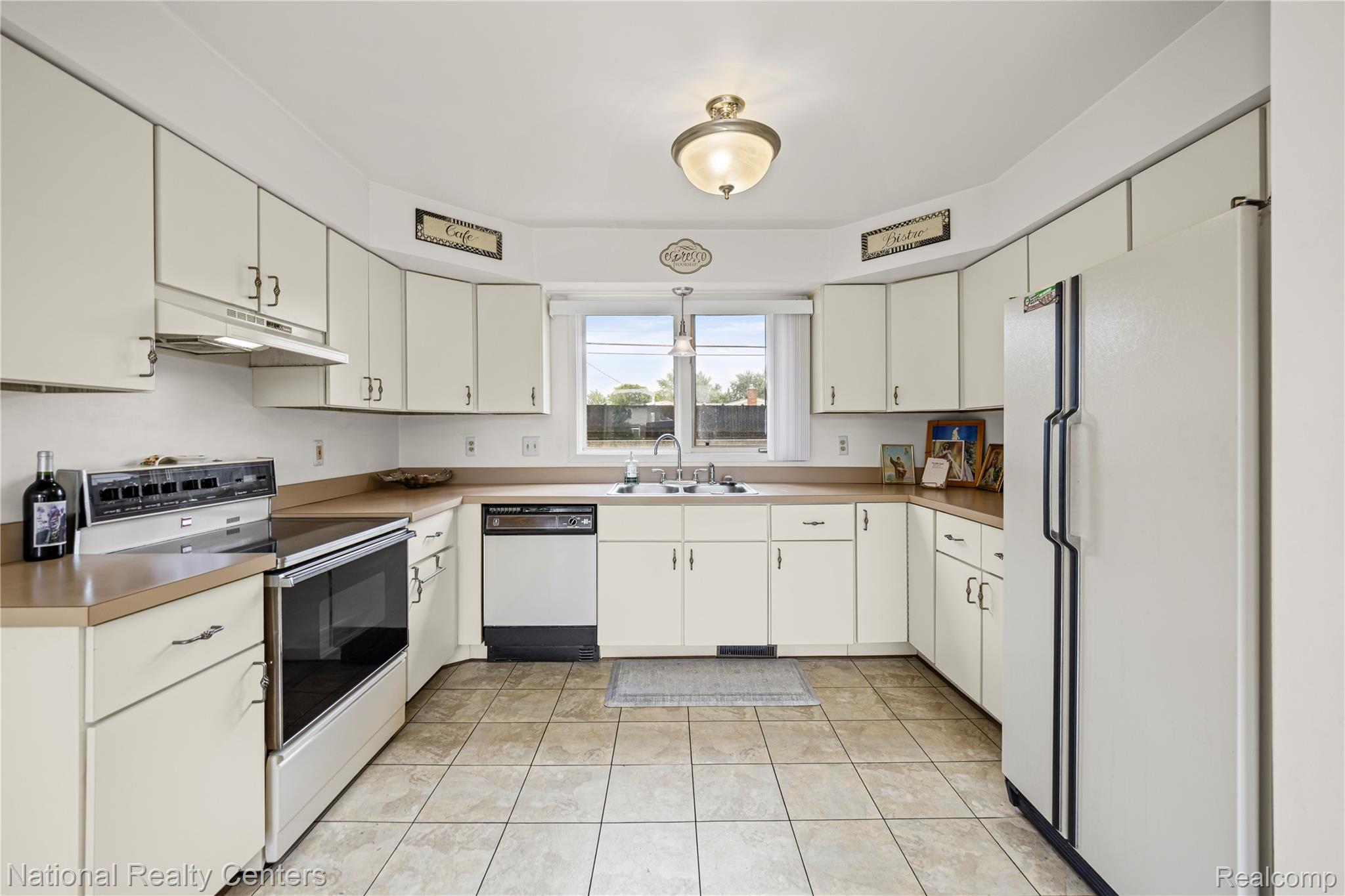 5274 East 14 Mile Road Warren, MI 48092 - Photo 10 of 31 U-shaped kitchen featuring white cabinetry, a built-in oven with an electric cooktop, a double-basin sink, and tiled flooring