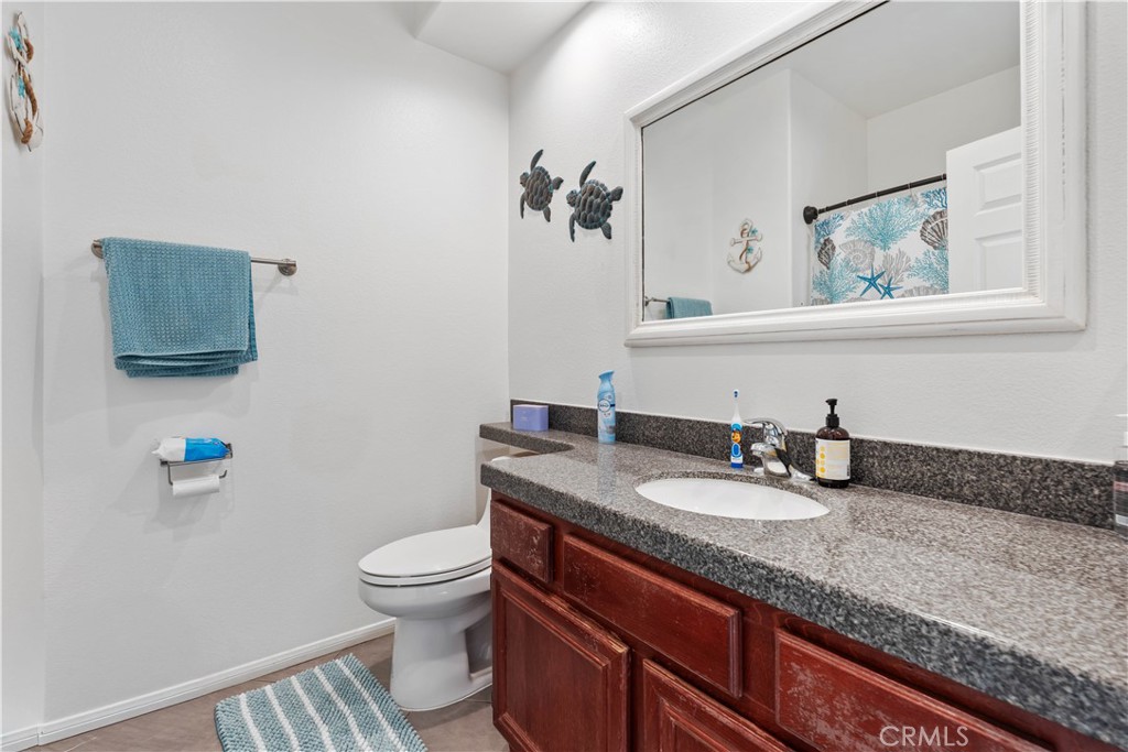 236 Jam Street Hemet, CA 92544 - Photo 19 of 36 a bathroom with a granite countertop sink a toilet and a mirror