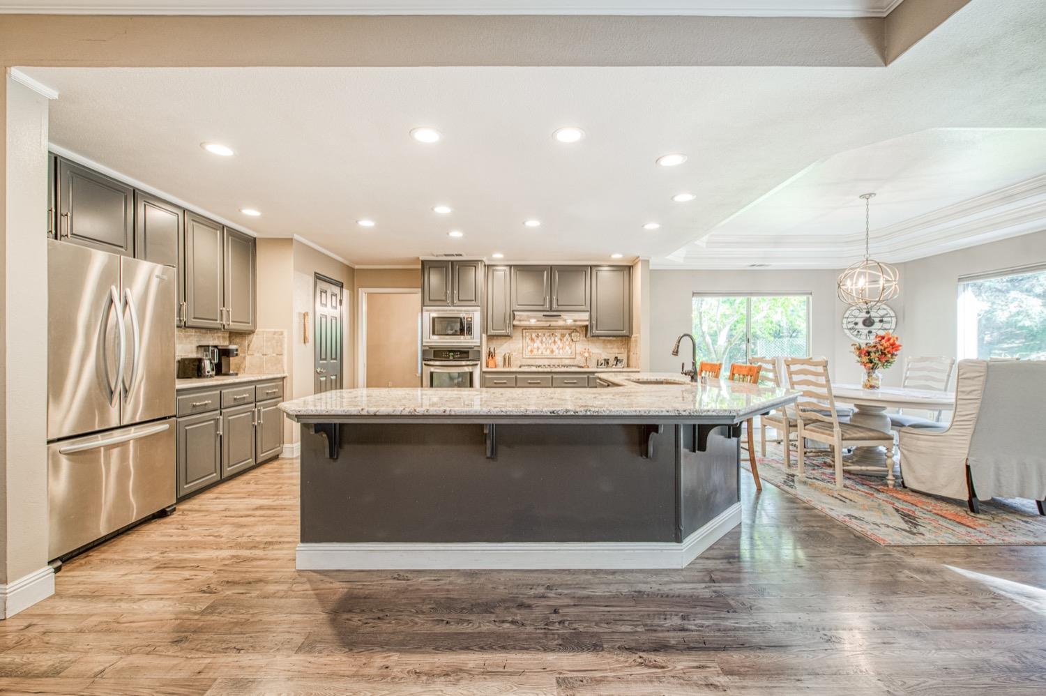 205 West Ridgepoint Drive Fresno, CA 93711 - Photo 19 of 49 a kitchen with stainless steel appliances granite countertop a stove top oven a sink dishwasher a refrigerator and a dining table with wooden floor