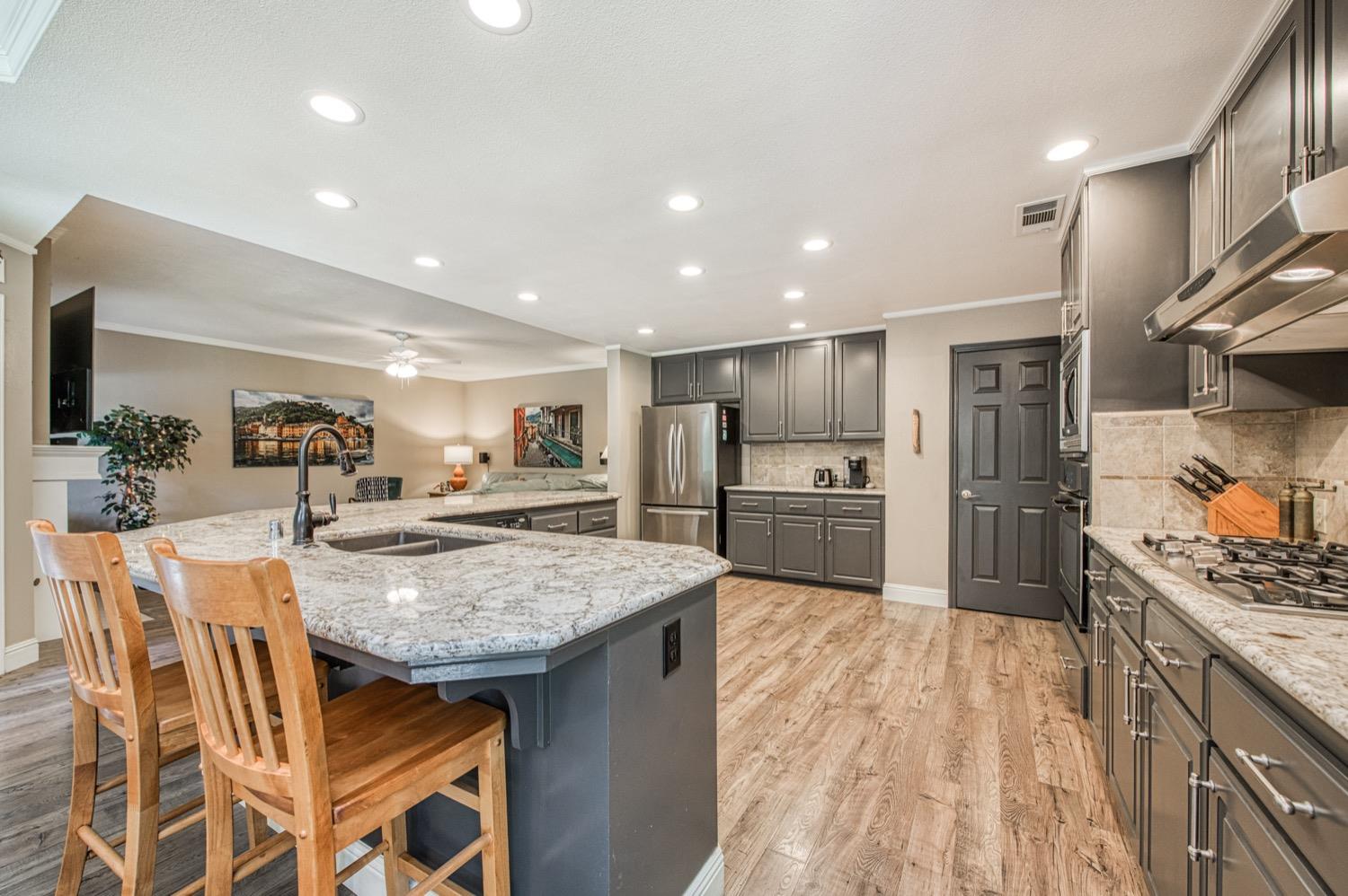 205 West Ridgepoint Drive Fresno, CA 93711 - Photo 24 of 49 a kitchen with stainless steel appliances granite countertop a stove top oven a sink dishwasher a dining table and chairs with wooden floor