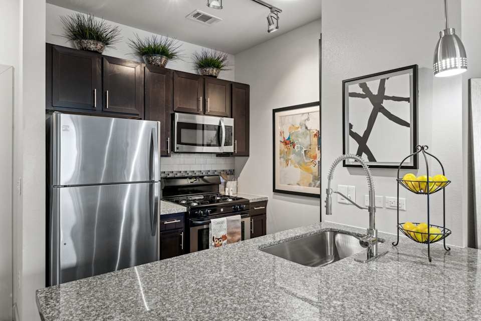 8800 South 1st Street, Unit 1124 Austin, TX 78748 - Photo 7 of 20 a kitchen with stainless steel appliances granite countertop a refrigerator a stove and a sink with wooden floor