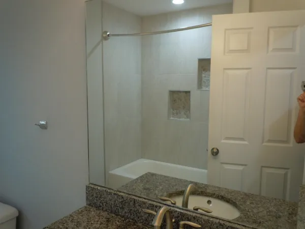 a bathroom with a granite countertop sink and shower