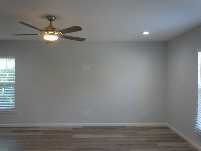 a view of an empty room with wooden floor and fan