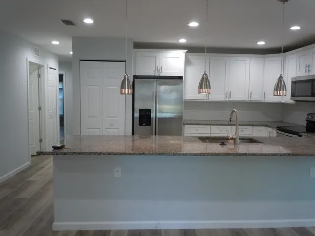 a kitchen with stainless steel appliances granite countertop a sink a refrigerator and a granite counter tops