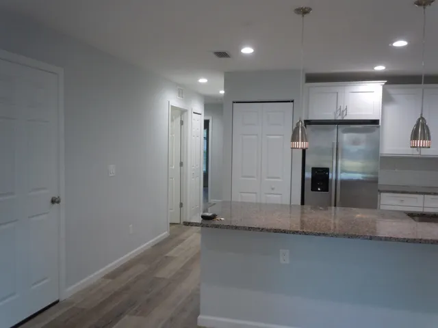 an empty room with wooden floor and a kitchen view