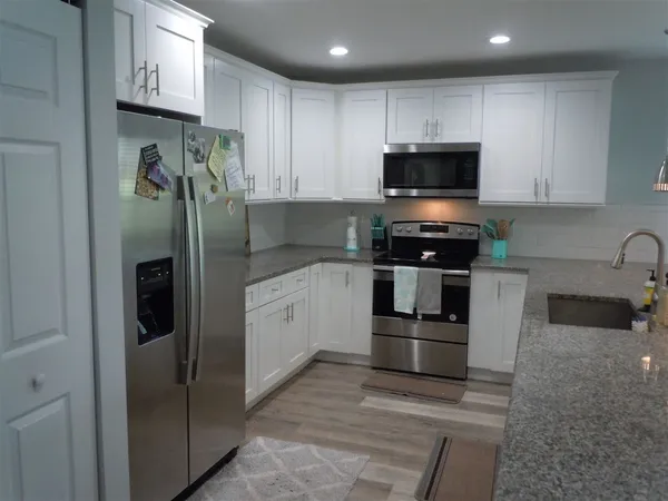 a kitchen with stainless steel appliances granite countertop a refrigerator and a stove top oven