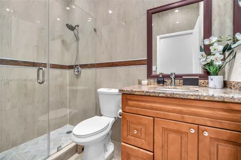 a bathroom with a granite countertop sink a toilet a mirror and shower
