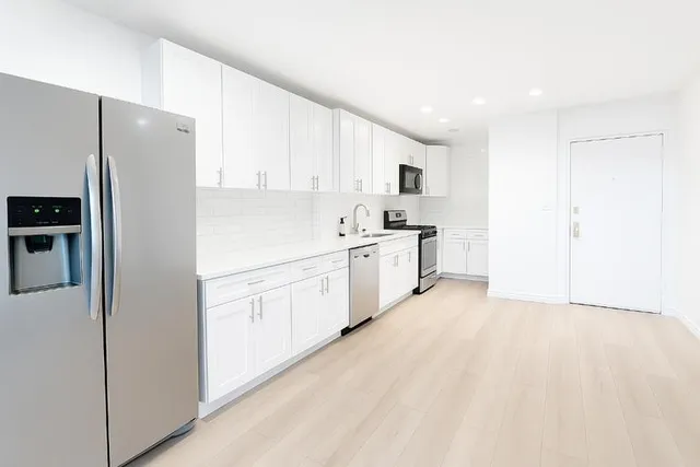 a kitchen with white cabinets and refrigerator