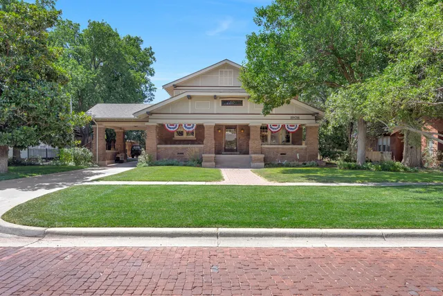 a view of a white house next to a yard with big trees