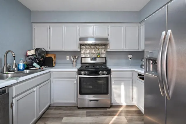 a kitchen with stainless steel appliances granite countertop a stove a refrigerator and a sink with cabinets