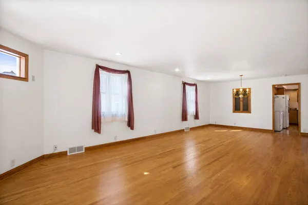 a view of an empty room with window and wooden floor