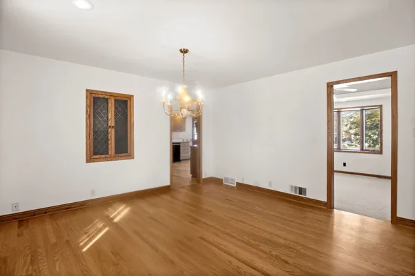 a view of an empty room with window and wooden floor