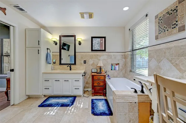 a bathroom with a sink mirror vanity and bathtub