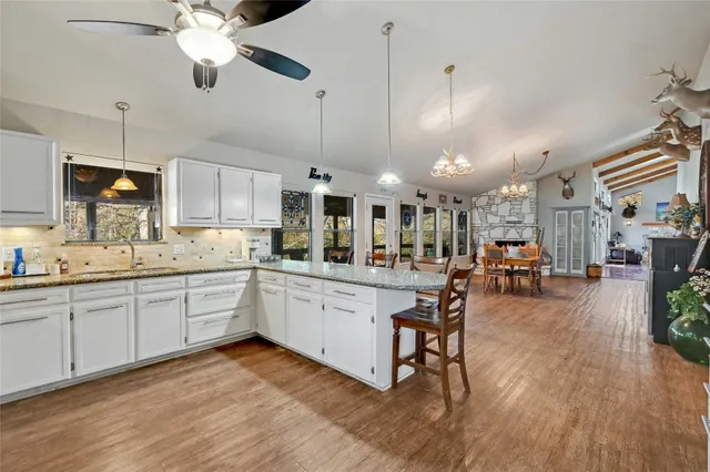 a kitchen with stainless steel appliances kitchen island hardwood floor sink stove dining table and chairs