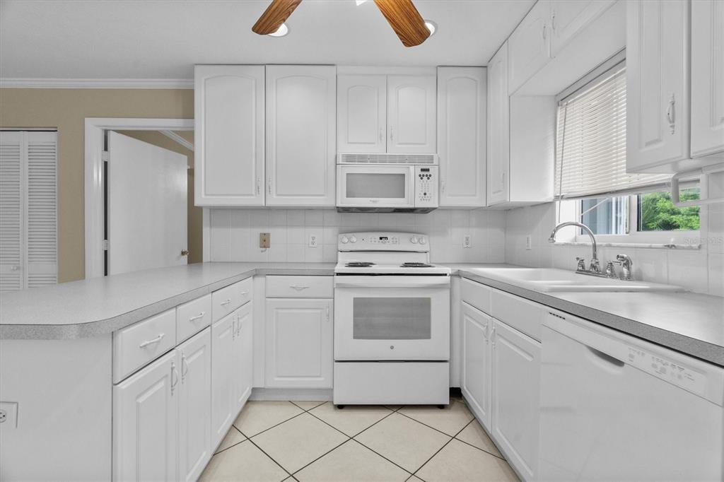 2660 Lear Road Englewood, FL 34224 - Photo 13 of 42 a kitchen with white cabinets appliances and a sink