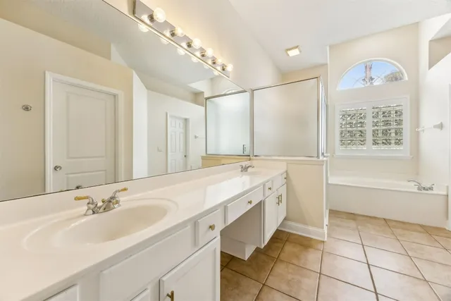 a spacious bathroom with a tub sink and mirror