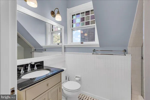 a bathroom with a granite countertop sink vanity mirror and toilet