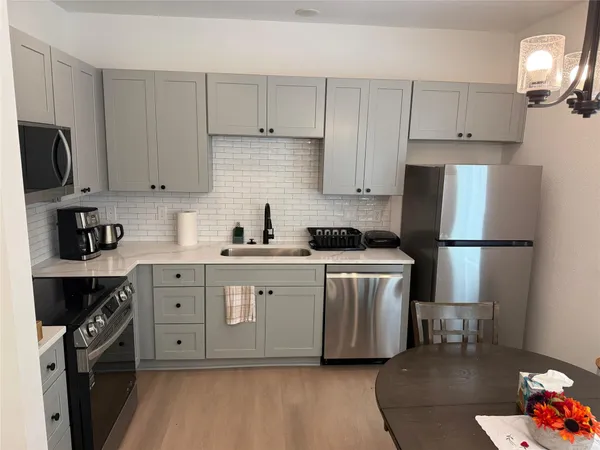 a kitchen with stainless steel appliances white cabinets sink and a refrigerator