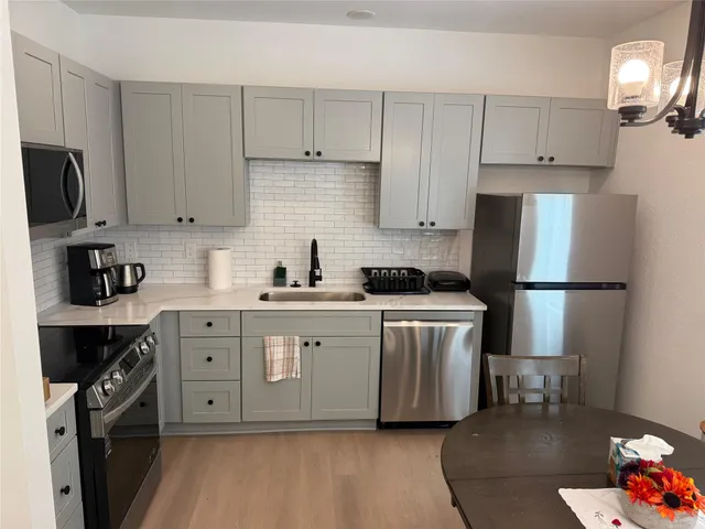 a kitchen with stainless steel appliances white cabinets sink and a refrigerator