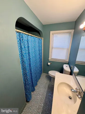 an empty room with chandelier fan and windows