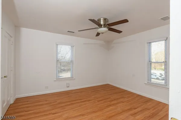 a view of empty room with wooden floor and fan