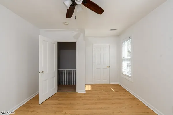 a view of an empty room with chandelier fan and window