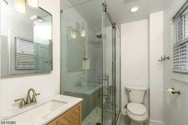 a bathroom with a granite countertop sink a toilet and shower