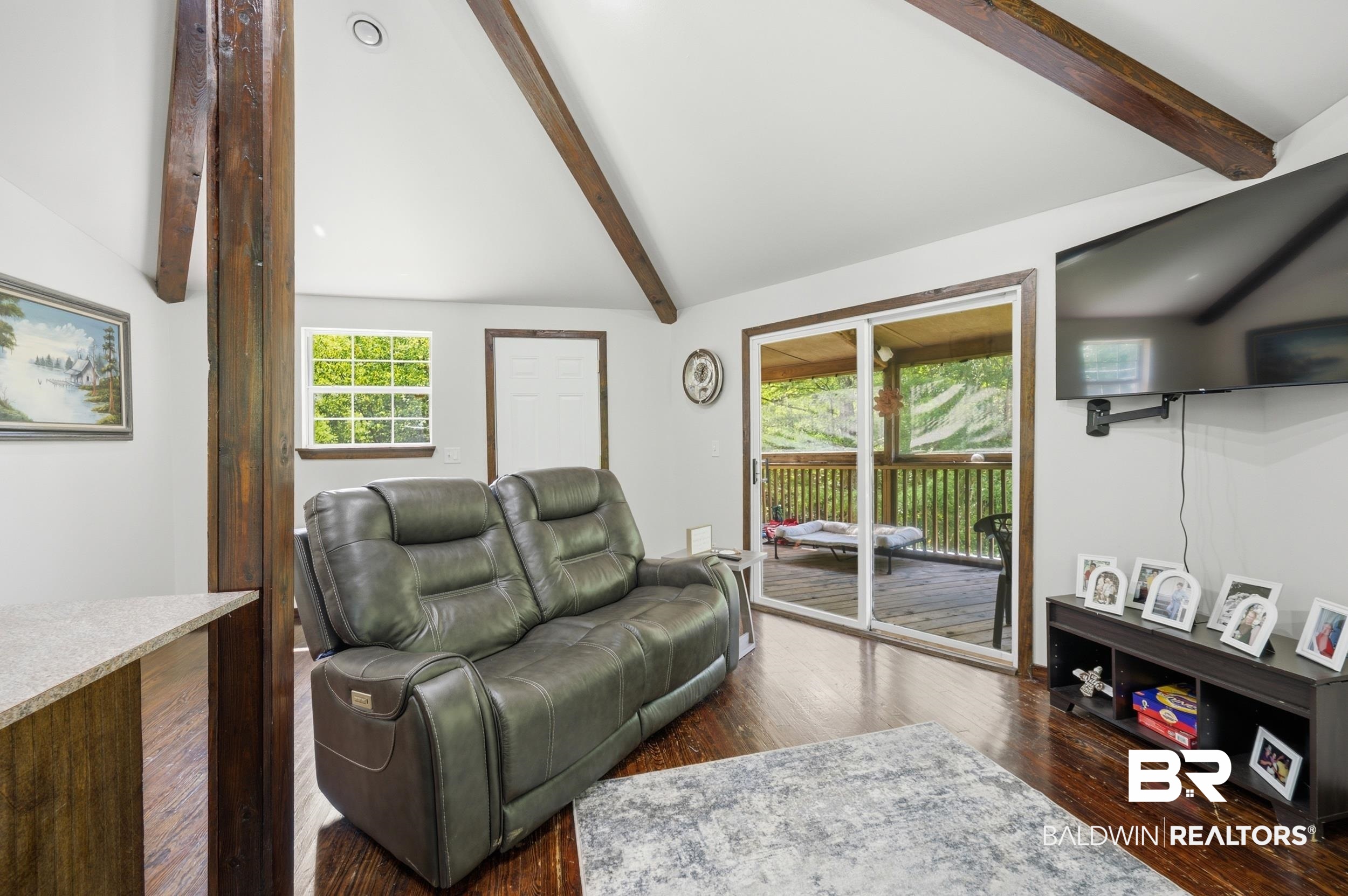 42080 Bayou Road Bay Minette, AL 36507 - Photo 18 of 43 Living area featuring vaulted ceilings with exposed wood beams, wood-finish flooring, and a sliding glass door to an outdoor deck