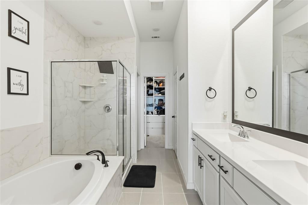 1128 Queensdown Way Forney, TX 75126 - Photo 17 of 30 Spacious bathroom featuring a deep soaking tub, a walk-in shower with white marbled tile surround, and a dual-sink vanity with ample counter space