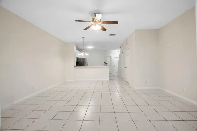 an empty room with white walls and ceiling fan