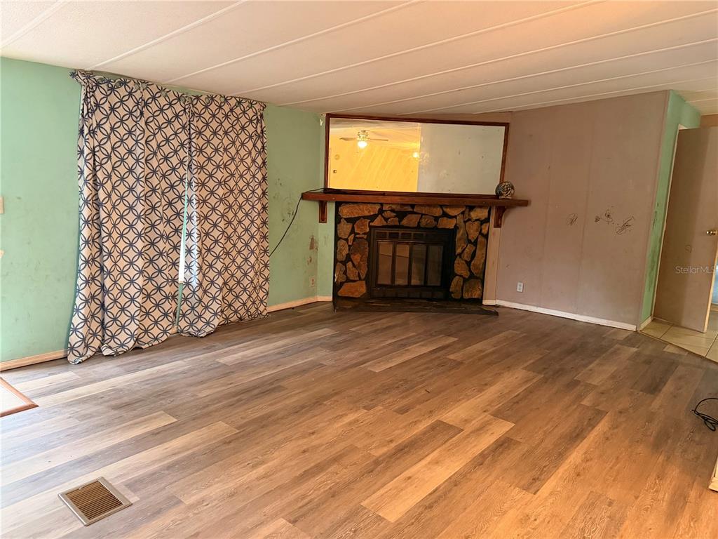 24021 Armadillo Road Astor, FL 32102 - Photo 6 of 38 an empty room with wooden floor and windows