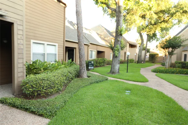 a view of a brick house with a big yard and large trees
