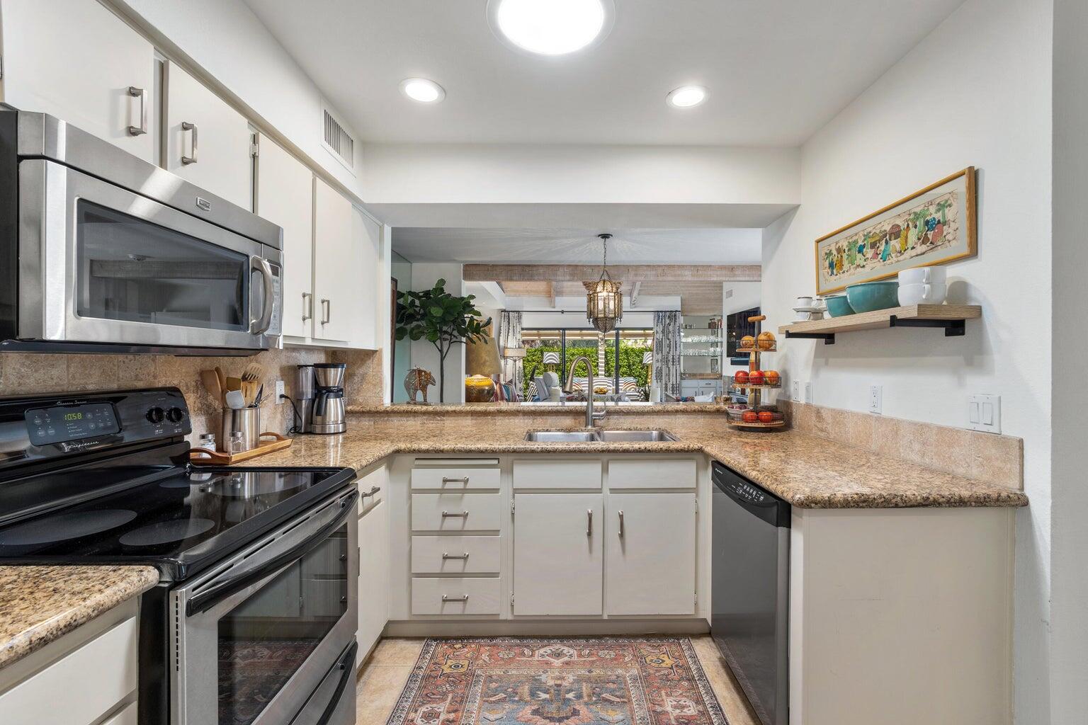 303 Forest Hills Drive Rancho Mirage, CA 92270 - Photo 23 of 71 a kitchen with stainless steel appliances granite countertop a sink stove and microwave