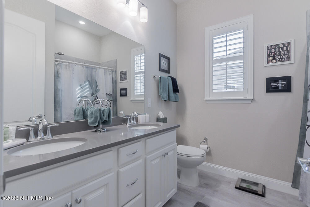 191 Enrede Lane St. Augustine, FL 32095 - Photo 24 of 44 a bathroom with a granite countertop sink a toilet and a large mirror