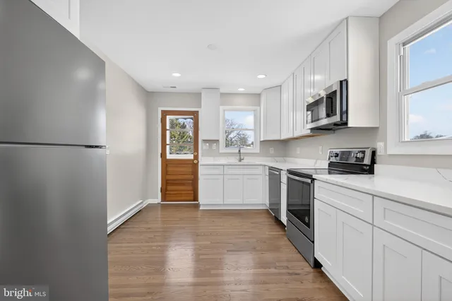 a kitchen with white cabinets stainless steel appliances and a window