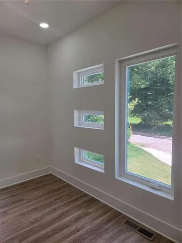 a view of an empty room with wooden floor and a window