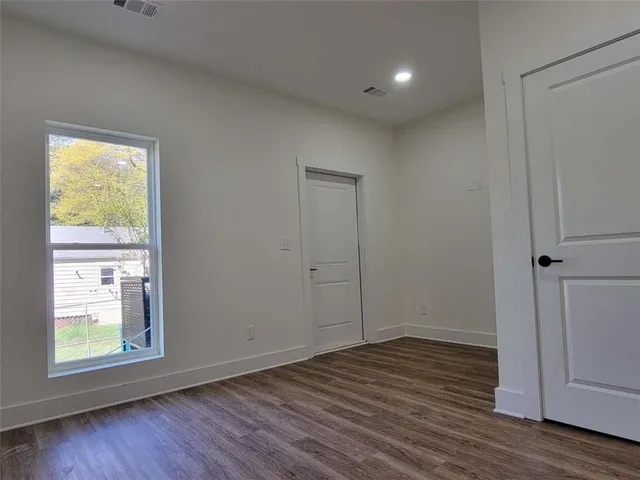 a view of an empty room with wooden floor and a window