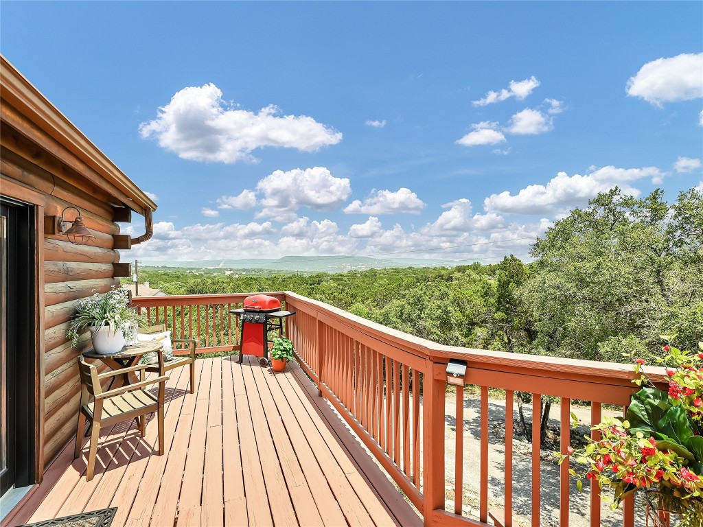 18304 West Reed Park Road Jonestown, TX 78645 - Photo 11 of 24 An elevated wooden deck overlooks rolling green treetops under a bright blue sky.