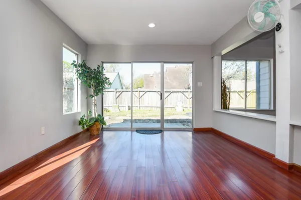 an empty room with wooden floor and windows