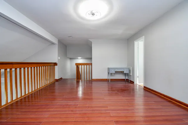 a view of an empty room with wooden floor windows